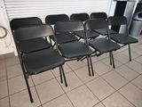 several black chairs are lined up in a row in front of a wall