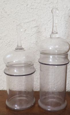 deux bocaux transparents avec leurs couvercles, posés sur une table en bois