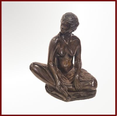 une statue en bronze représentant une femme assise sur un coussin