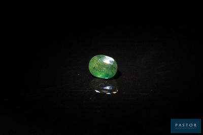 a close up of a green gemstone on a black surface