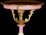 a pink table with gold trim and a gold plate on top