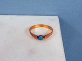 une bague sertie d'une pierre bleue, posée sur une table