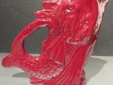 a red vase with a fish on it sitting on a table