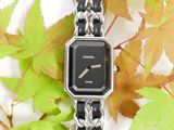 a black and silver watch sitting on a chain bracelet