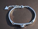 a silver bracelet with a diamond on it on a table
