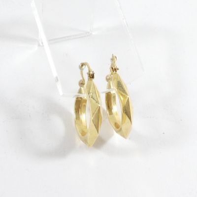 une paire de boucles d'oreilles en or sur une surface blanche