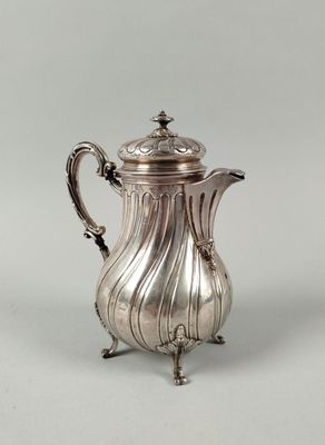 une cafetière ancienne en argent, posée sur un socle et munie d'un couvercle