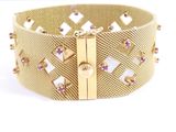 a close up of a gold bracelet with pink stones on it