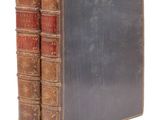 deux vieux livres sont empilés l'un sur l'autre sur une surface blanche