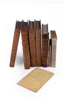 several old books are stacked on top of each other on a white surface