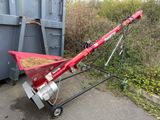 un épandeur rouge posé devant une benne à ordures