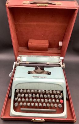 une vieille machine à écrire dans un étui, posée sur une table
