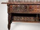 an old wooden table with a carved top and two drawers