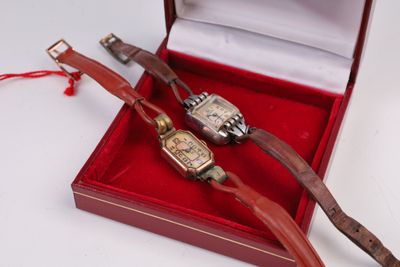 deux montres posées dans une boîte rouge sur une surface blanche