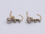 two pairs of gold and diamond earrings on a white surface