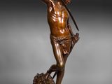 une statue en bronze représentant un homme tenant une épée, debout sur un rocher