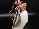 a white and tan bag with a brown strap on a black background