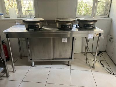 trois casseroles posées sur une table dans une cuisine avec une fenêtre