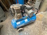 un compresseur d'air bleu posé par terre dans un garage