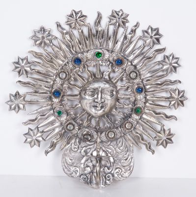 a silver brooch with a face surrounded by stars