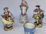 trois figurines représentant des personnes sont assises à côté d'une tasse posée sur une table