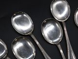 six silver spoons are lined up on a black surface