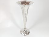 a silver vase that is sitting on a white surface