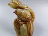 two birds sitting on top of a vase on a white surface