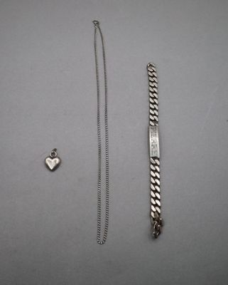 un bracelet en argent et une breloque en forme de cœur en argent posés sur une table