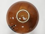 a brown bowl with a black handle on a white table