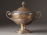 une coupe ancienne en argent, munie d'un couvercle et d'anses, posée sur un support gris