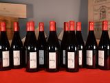 six bottles of red wine are lined up on a table