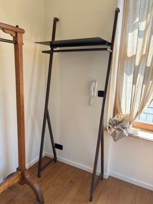 un porte-manteau dans un coin de la pièce, près d'une fenêtre
