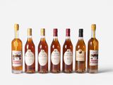 six bottles of wine are lined up in a row on a white surface