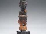 une statue en bois d'un homme avec un chapeau sur la tête