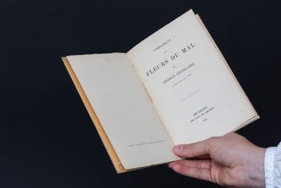 une personne tenant un livre ouvert à la main, sur fond noir