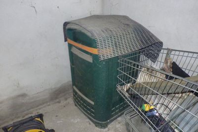 un oiseau dans une cage à côté d'une poubelle