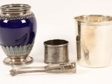 a blue vase, a silver cup, and a spoon on a table
