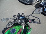 a green motorcycle parked in a parking lot next to a black car