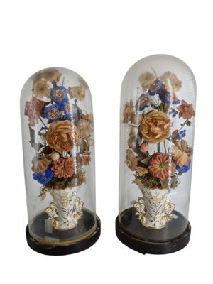 pair of decorative glass vases with flowers in them on wooden bases