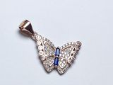 pendentif papillon orné de cristaux bleus et blancs sur fond blanc