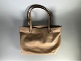 un sac fourre-tout en cuir beige accroché à un mur