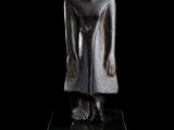 statue of a female figure on a black base against a black background