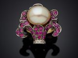 a white pearl and pink sapphire ring on a black surface