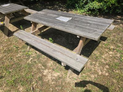 a picnic table with a sign on it in the grass