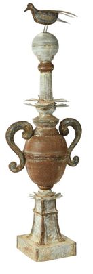un oiseau perché sur un vase posé sur un socle