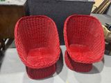 two red wicker chairs sitting on top of a table next to each other