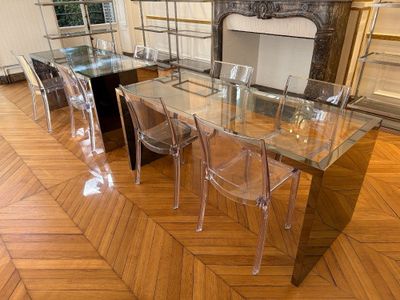une table de salle à manger en verre avec des chaises transparentes et une cheminée en arrière-plan