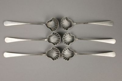 quatre cuillères en argent sont disposées en rangée sur une table