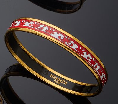 two bangles with red and white designs on them on a black surface